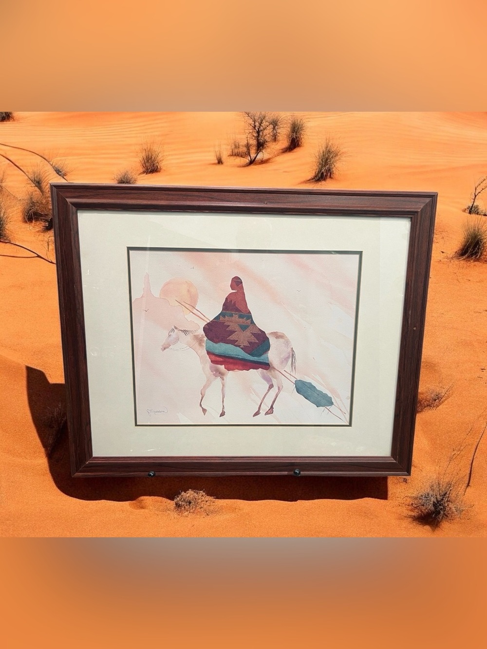 A framed print by JC Madden depicting a Native American on horseback at sunset.
